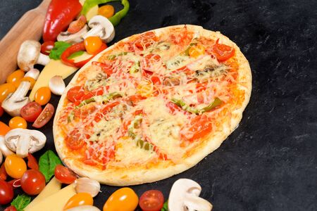 vegetarian pizza on a dark background. ingredients for cooking, tomatoes, mushrooms, peppers, Basil and cheese for pizza . space for text. the view from the top.の写真素材