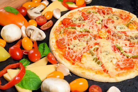 vegetarian pizza on a dark background. ingredients for cooking, tomatoes, mushrooms, peppers, Basil and cheese for pizza . space for text. the view from the top.の写真素材