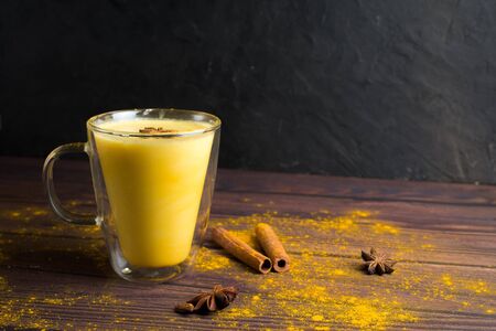 Golden milk turmeric latte with turmeric powder and ingredients in a clear glass on a dark background. A traditional Indian drink is turmeric milk. The view from the top, space for text.の写真素材