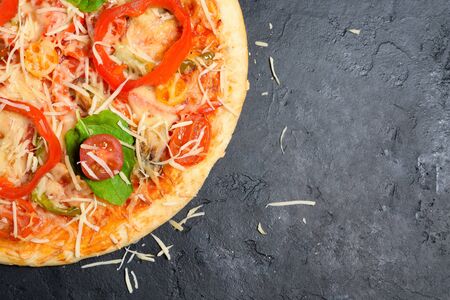 part of a round vegetarian pizza on the side of the frame on a dark background. ingredients vegetables and cheese for pizza . space for text. the view from the top.の写真素材