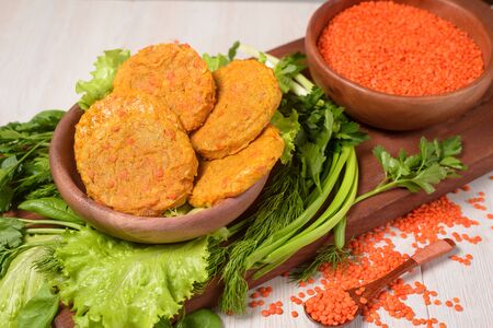 vegetarian meatless meatballs made of lentils and carrots in a wooden plate with vegetables and greens. healthy food. red lentils in a wooden plate on a light background. the view from the topの写真素材