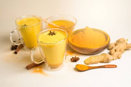 Indian traditional Golden milk with turmeric, ginger, spices, honey. healing effect of the drink. ingredients for a Golden drink on a light background. antiviral antioxidant. the view from the top.の写真素材