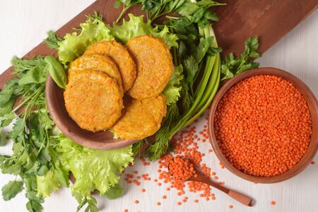 vegan lentil and carrot burgers in a wooden plate with green salad on a light background. vegetarian healthy food. lentils in a wooden plate.の写真素材