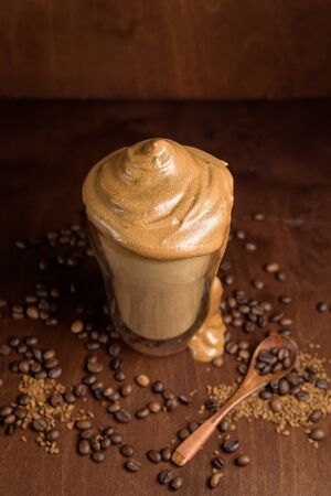 cold dalgon coffee in clear glasses on a dark wooden background. foam from sugar and instant coffee is whipped with a mixer over cold milk. Korean and Indian national whipped coffeeの写真素材