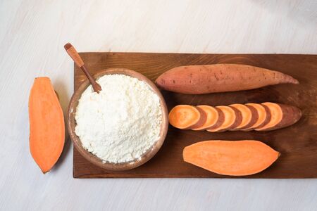 sweet potato flour in a wooden plate. sweet potatoes are a vegan organic ingredient for healthy eating on a light backgroundの写真素材