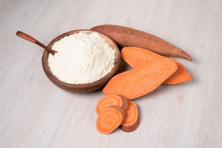 sweet potato flour in a wooden plate. sweet potatoes are a vegan organic ingredient for healthy eating on a light backgroundの写真素材