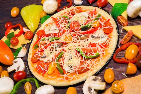 vegan pizza with vegetables, tomatoes, mushrooms, pepper. top view large view . ingredients for vegetarian pizza on a dark background.の写真素材