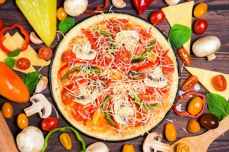 vegan pizza with vegetables, tomatoes, mushrooms, pepper. top view large view . ingredients for vegetarian pizza on a dark backgroundの写真素材