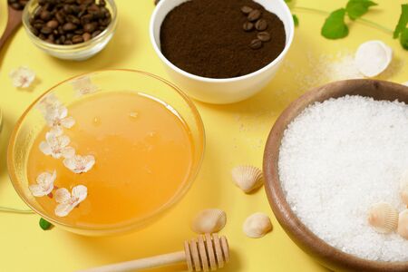 natural organic ingredients-sea salt, coffee scrub, honey and a hard body brush on a yellow background. home skin care for cellulite. concept of skin care, home Spa. the view from the topの写真素材