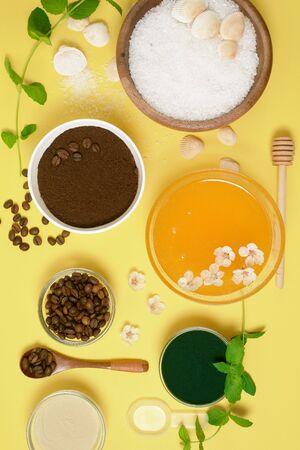 natural organic ingredients-sea salt, coffee scrub, honey and a hard body brush on a yellow background. home skin care for cellulite. concept of skin care, home Spa. the view from the topの写真素材