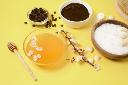 natural organic ingredients-sea salt, coffee scrub, honey and a hard body brush on a yellow background. home skin care for cellulite. concept of skin care, home Spa. the view from the topの写真素材