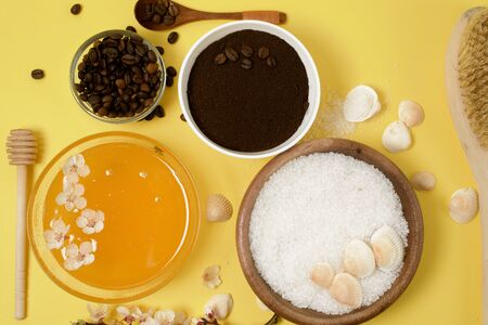 natural organic ingredients-sea salt, coffee scrub, honey and a hard body brush on a yellow background. home skin care for cellulite. concept of skin care, home Spa. the view from the topの写真素材