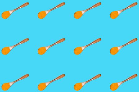 turmeric spoon pattern on a blue background. pattern of a wooden spoon with turmeric powder.の写真素材