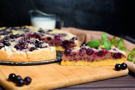 pie with black currant and shortbread, fresh berries. the pie is cut into pieces and the top is sprinkled with powdered sugar . close-up of a piece in the pie section.の写真素材