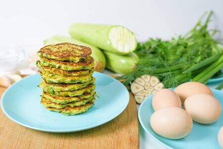 veggie fried pancakes with zucchini and greens on a blue plate on a light background on a wooden Board . recipe with the addition of eggs and flour. top view, selective focus, space for text.の写真素材
