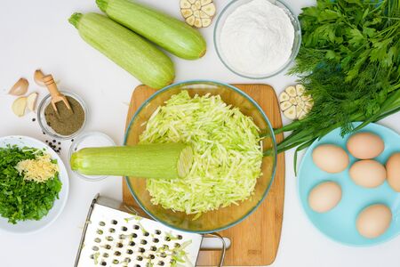 step by step recipe to cook zucchini pancakes and greens on a light background on a wooden Board . recipe with the addition of eggs and flour, garlic, pepper. the view from the top. grate the zucchini.の写真素材