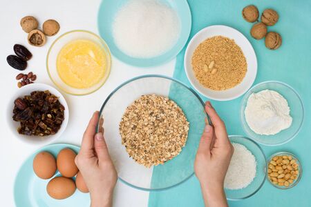 ingredients for the recipe homemade oatmeal cookies with dates, peanuts , coconut shavings, eggs, flour, salt in glazed plates on a light background. the view from the top.の写真素材