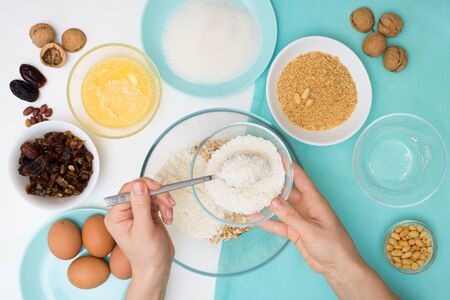 ingredients for the recipe homemade oatmeal cookies with dates, peanuts , coconut shavings, eggs, flour, salt in glazed plates on a light background. the view from the top.の写真素材