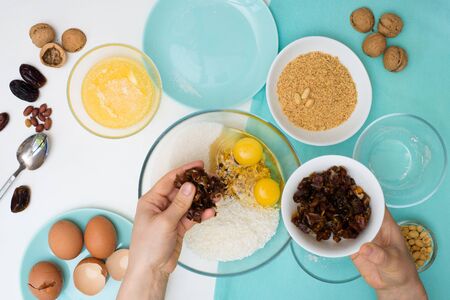 ingredients for the recipe homemade oatmeal cookies with dates, peanuts, coconut chips in glass plates on a light background. the view from the top, mixing with your hands ingredients.の写真素材