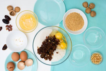 ingredients for the recipe homemade oatmeal cookies with dates, peanuts , coconut shavings, eggs, flour, salt in glazed plates on a light background. the view from the top.の写真素材