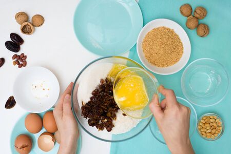 ingredients for the recipe homemade oatmeal cookies with dates, peanuts, coconut chips in glass plates on a light background. the view from the top, mixing with your hands ingredients.の写真素材