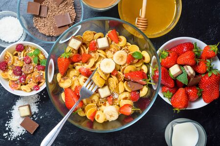 mini pancake cereal bowl with fresh strawberries banana chocolate, coconut shavings and honey in small plates. the view from the top . the trend of self-isolation.の写真素材