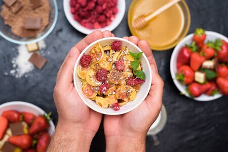 mini pancake cereal bowl with fresh strawberries banana chocolate, coconut shavings and honey in small plates. the view from the top . the trend of self-isolation.の写真素材