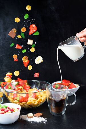 mini pancake bowl for cereals with fresh strawberries, banana, chocolate, coconut mint. the tendency to self-isolation. levitation of tiny pancakes into a plate on a black background.の写真素材