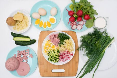 step by step recipe for Russian cold okroshka soup, ingredients for homemade okroshka-sausage, greens, eggs, cucumbers, potatoes, radishes. top view on a light background.の写真素材