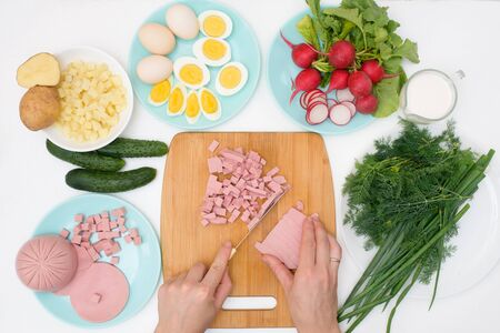 step by step recipe for Russian cold okroshka soup, ingredients for homemade okroshka-sausage, greens, eggs, cucumbers, potatoes, radishes. top view on a light background.の写真素材