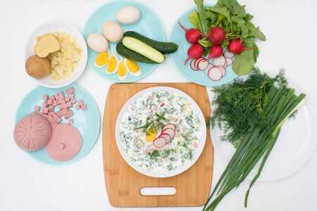 step by step recipe for Russian cold okroshka soup, ingredients for homemade okroshka-sausage, greens, eggs, cucumbers, potatoes, radishes. top view on a light background.の写真素材