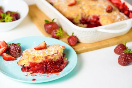 homemade strawberry cobbler made from ripe fresh strawberries. cut strawberry pie on a blue plate on a light background.の写真素材