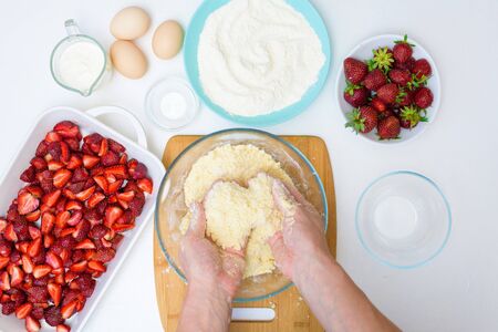 step by step recipe strawberry cobbler homemade from ripe fresh strawberries and shortbread on a light background, top view. ingredients for strawberry pie. knead the shortbread dough.の写真素材