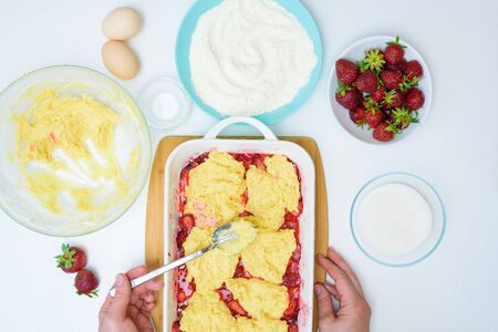 step by step recipe strawberry cobbler homemade from ripe fresh strawberries and shortbread on a light background, top view. cut the strawberries and mix with the starch, lay out the dough.の写真素材