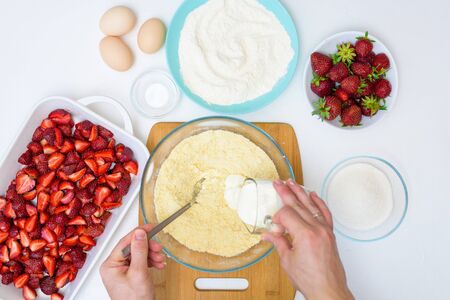 step by step recipe strawberry cobbler homemade from ripe fresh strawberries and shortbread on a light background, top view. ingredients for strawberry pie. knead the shortbread dough.の写真素材