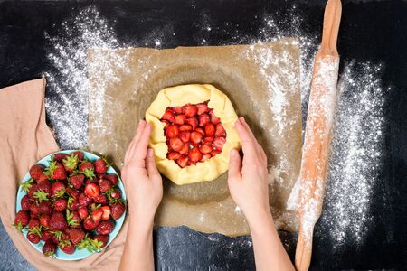 step by step recipe the process of making galetta with strawberries at home, top view on a dark background, ingredients for strawberry pie.の写真素材