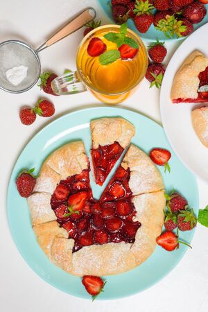 homemade strawberry Biscuit with fresh ripe strawberries on blue and white plates with tea on a light background, top view.の写真素材