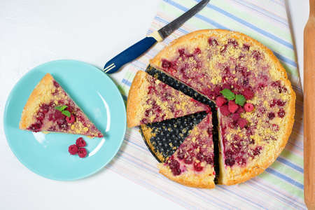 homemade raspberry pie with short pastry, ripe strawberries and cottage cheese cut into pieces on blue plates on a light background. top view.の写真素材