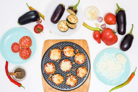 step-by-step recipe for homemade vegan pizza with eggplant for a bite, tomatoes, peppers, mozzarella. hands of a woman preparing a pizza with a view from above. light backgroundの写真素材