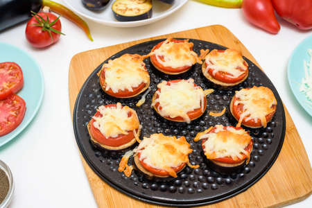 step-by-step recipe for homemade vegan pizza with eggplant for a bite, tomatoes, peppers, mozzarella. hands of a woman preparing a pizza with a view from above. light backgroundの写真素材