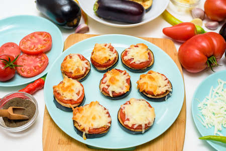 cooking homemade vegan pizza eggplant bites, tomatoes, peppers, mozzarella on a blue plate. eggplant stacked on a light background.の写真素材