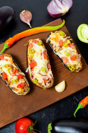 preparation homemade stuffed eggplant with vegetables and mozzarella cheese, ingredients tomatoes, peppers, onions, eggplant. on a dark background top view.の写真素材