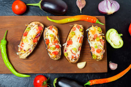 preparation homemade stuffed eggplant with vegetables and mozzarella cheese, ingredients tomatoes, peppers, onions, eggplant. on a dark background top view.の写真素材