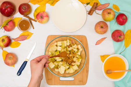 Autumn baking concept. step-by-step recipe for baking a traditional autumn Apple pie, copy the space on a light background. cut apples and mix with cinnamon and sugar.の写真素材
