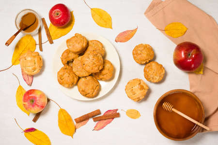 autumn baking concept with seasonal apples and cinnamon honey. Apple cupcakes and muffins on a plate top view on a light background with autumn yellow leavesの写真素材