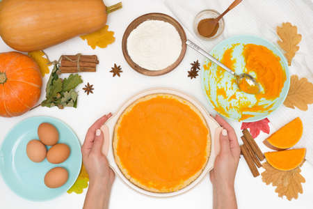 step-by-step recipe for cooking homemade pumpkin pie with spices ingredients on plates top view on a light background. put the filling on the baked cake and distribute.の写真素材