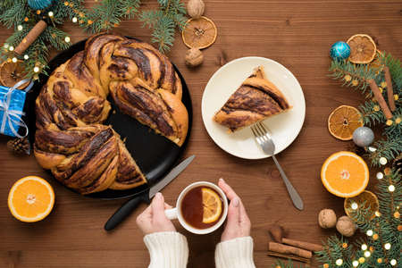 chocolate Christmas grandmother in the form of a wreath with orange syrup on a plate cut into pieces. Christmas decorations on a wooden table.の写真素材