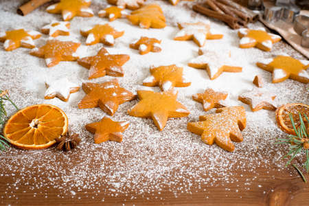 Homemade gingerbread cookies stars, decorated with powdered sugar and surrounded by spruce branches and dried oranges, cinnamon. new year's composition 2021.の写真素材