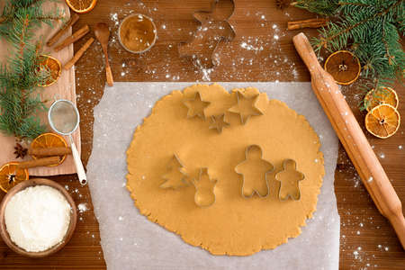cut gingerbread out of the dough using a gingerbread mold, top view, rolling pin, cinnamon and dried orange next.の写真素材
