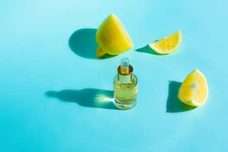 face serum with citrus fruit lemon and vitamin C in a glass bottle with a pipette on a blue background, the concept of self-care skin care at home.の写真素材